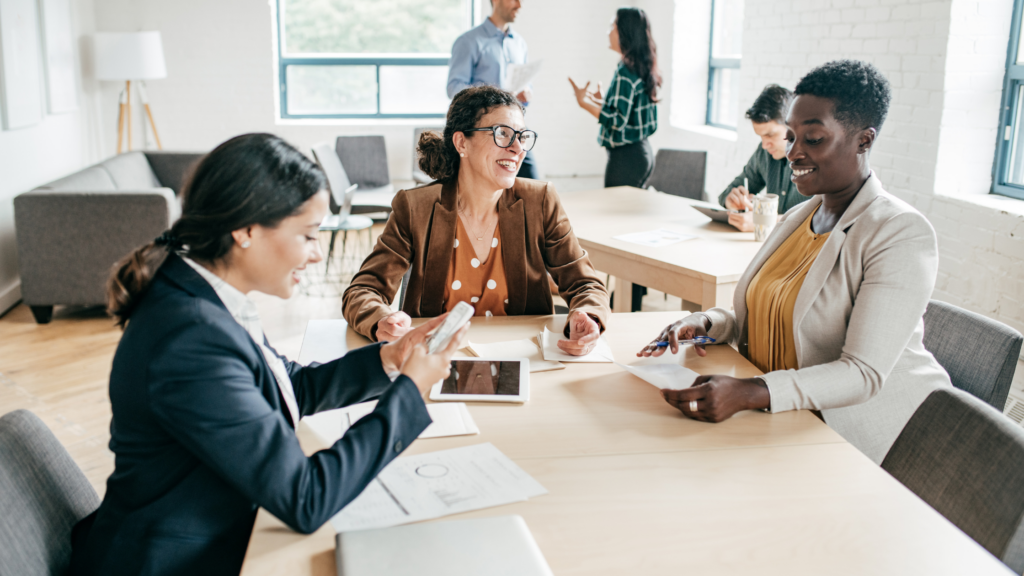 Three female accountants gather at a table to discuss accounting and using ai technology in finance