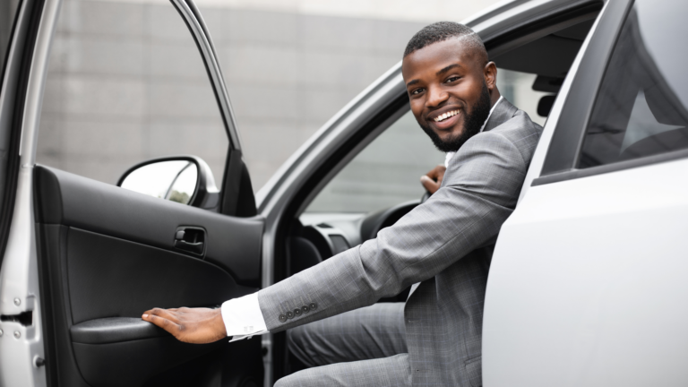 A man opening his car door and smiling. Small business owners can donate their car as a tax deduction.