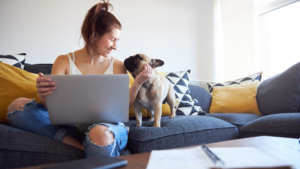 Woman sitting on the couch with a laptop and her dog