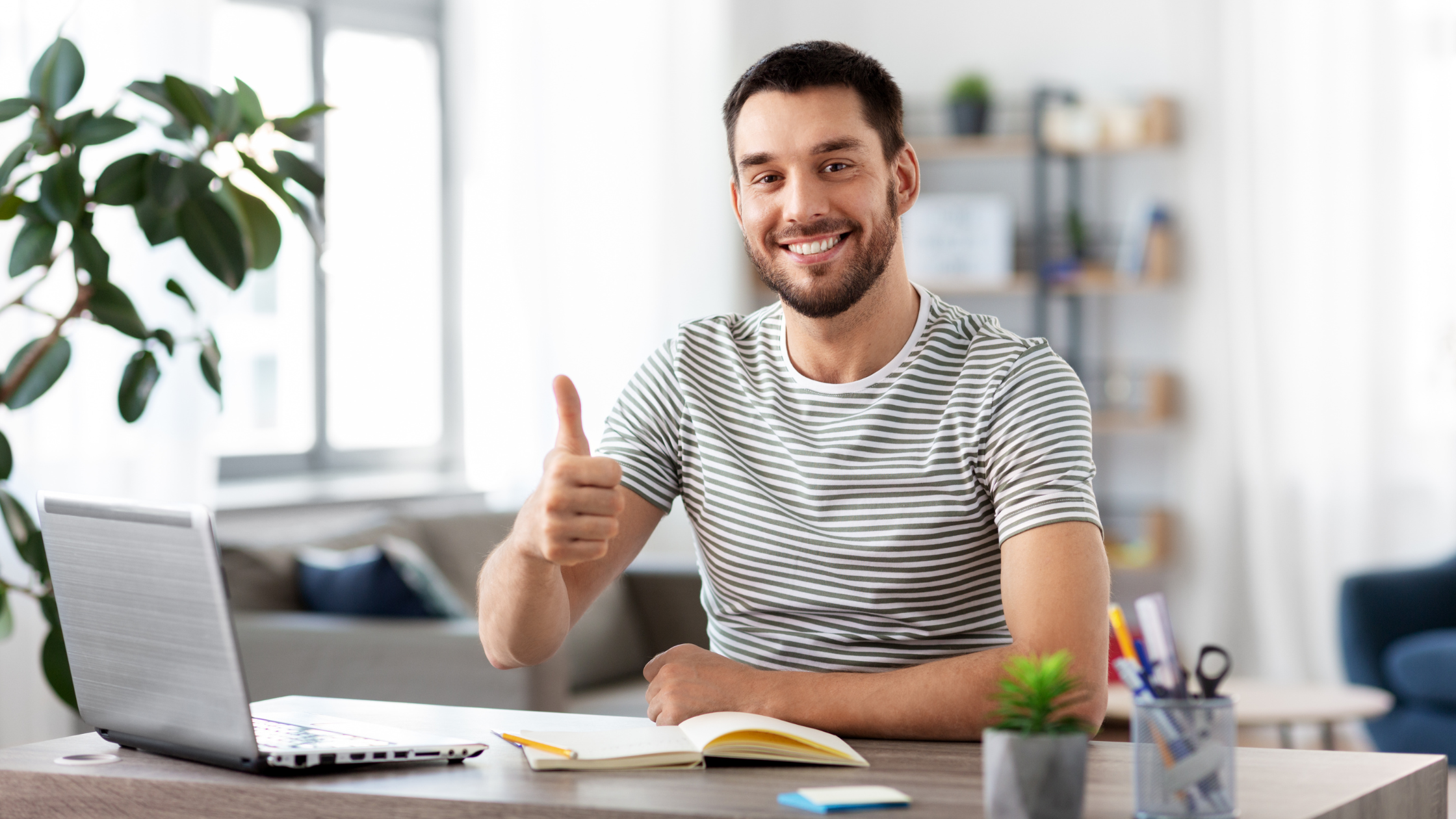 Freelancer gives a thumbs up while working at a laptop on a desk